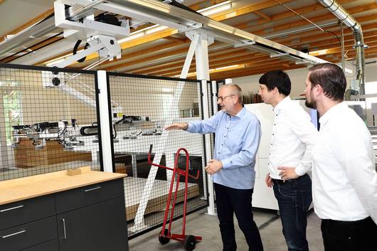 Andreas Lewerken (von links) erklärt Patrick Puhlmann und Mathias Bölt das neue Roboterlager in der Tischlerei.