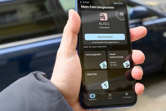 Eine Person hält ein Smartphone abgebildet ist die i-Kfz App.