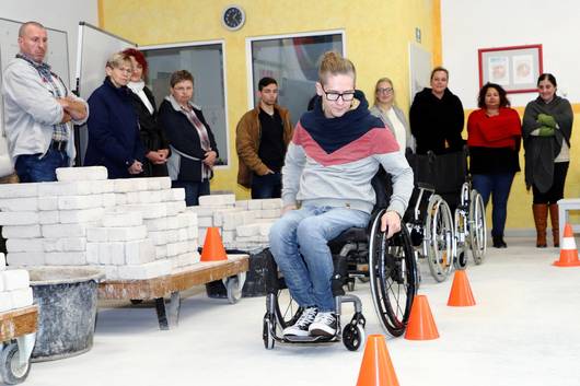 Thomas Rösicke zeigt den Teilnehmenden, wie der Rollstuhlparcours zu absolvieren ist.