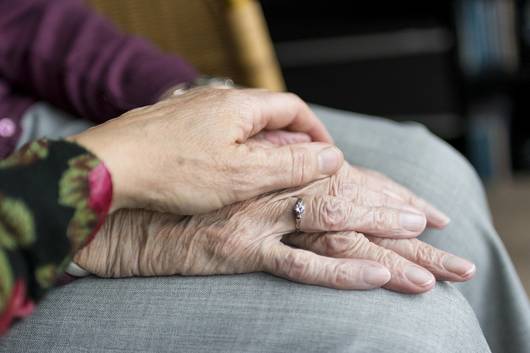 Eine jüngere Person legt ihre Hand auf die einer älteren Person.
